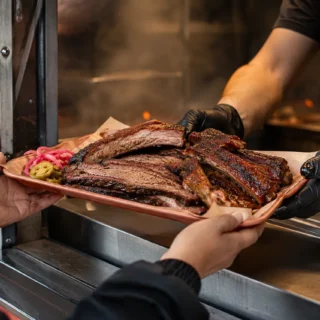 BBQ, a tray of sliced brisket and ribs handed across a BBQ food truck serving window