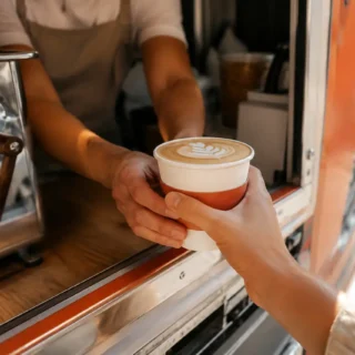 Coffee, a fresh latte handed across a mobile coffee truck serving window