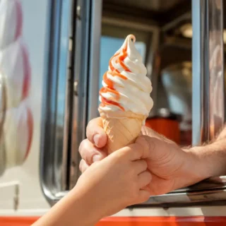 Ice Cream, a swirled soft serve cone handed through a bright ice cream truck serving window